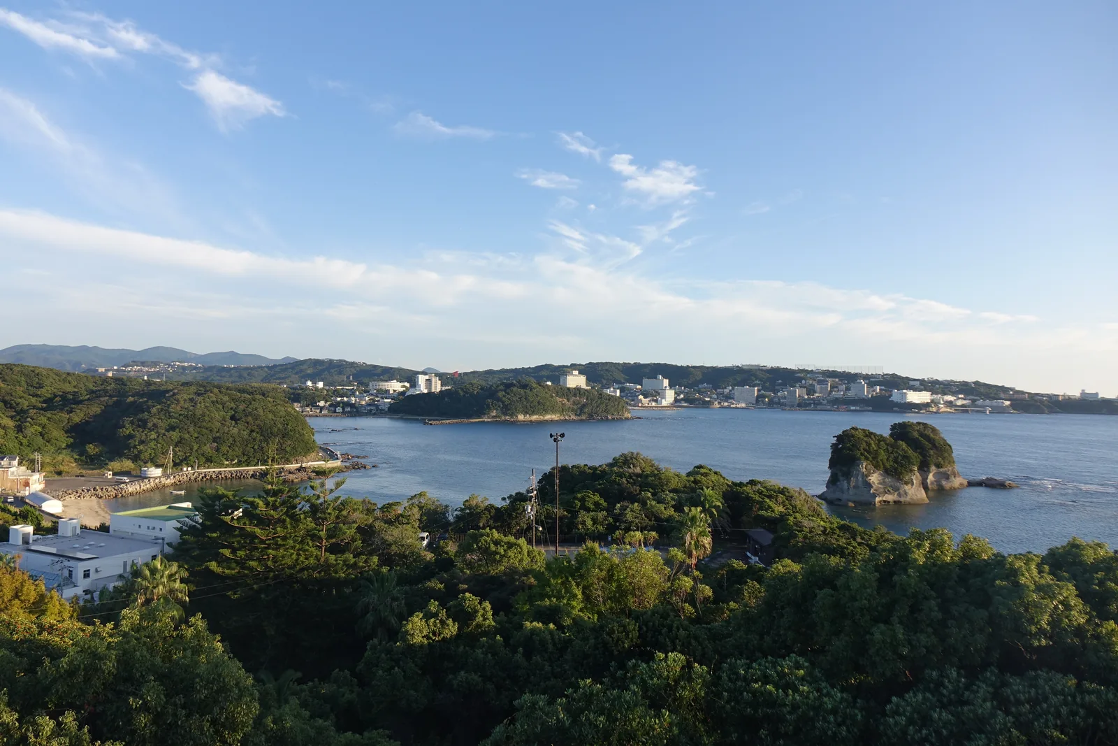 自新館屋頂望向陸地一側，前景是樹林，中景是一片海灣與灣岸的建築，遠方是白濱的市街與山
