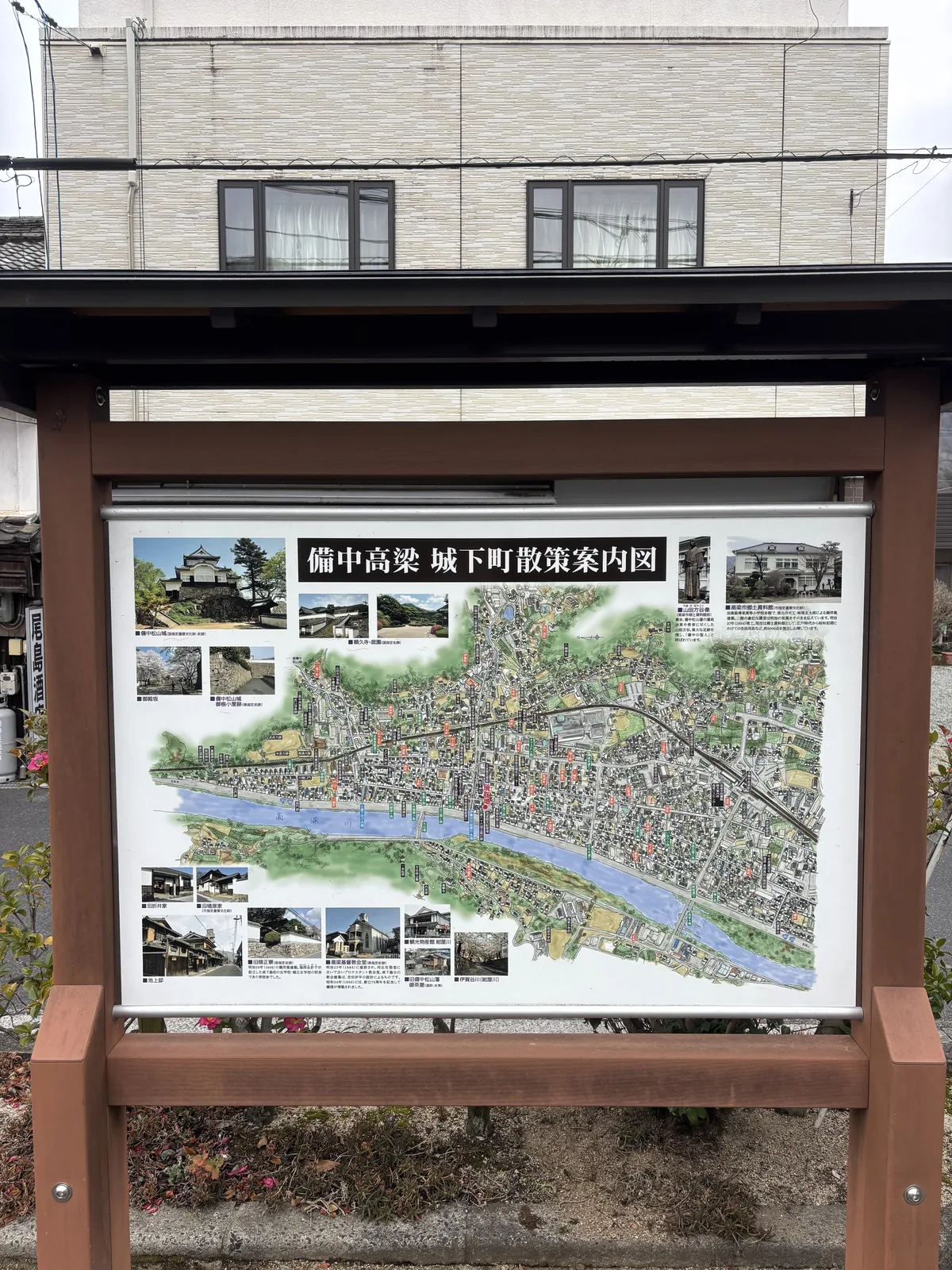 城下町的散策案內看板，木框內是一張彩色的城下町地圖，中央是高梁川與市街，四周配有名所的照片，看板上方有小型的屋簷